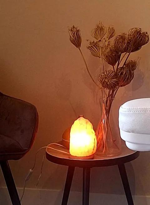 Een zoutlamp en droogbloemen naast de behandelstoel in de salon
